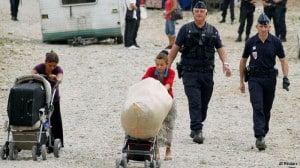 Roma women and their babies are escorted from their camp by a policeman in France 