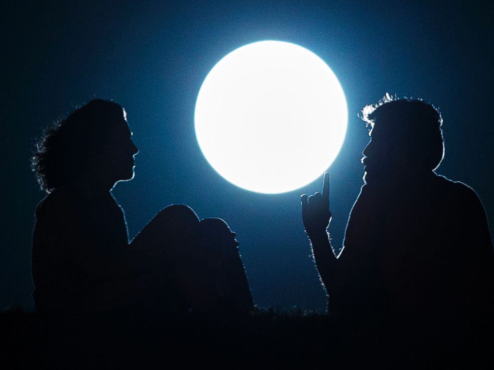 A couple talk as they sit against the perigee moon, also known as a supermoon, in Madrid, Aug. 10, 2014. Andres Kudacki/AP Photo