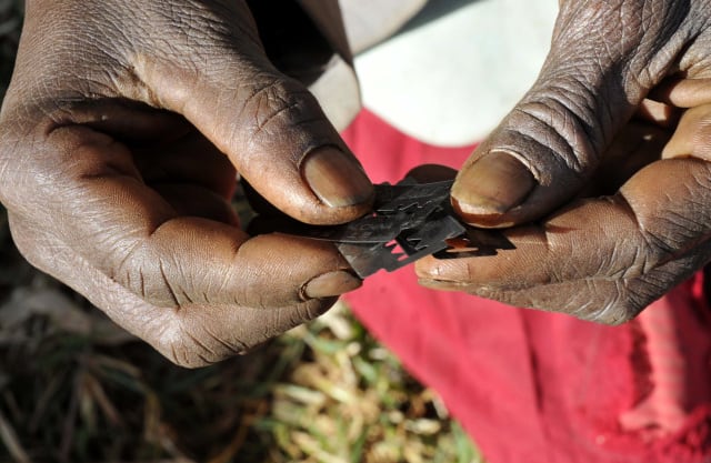 Prisca Korein, a 62-year-old traditional surgeon, holds razor blades before carrying out female genital mutilation on teenage girls from the Sebei tribe in Bukwa district, about 357 kms (214 miles) northeast of Kampala, December 15, 2008. The ceremony was to initiate the teenagers into womanhood according to Sebei traditional rites. Credit: James Akena 