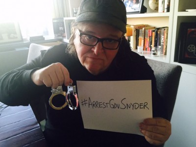 Michael Moore holds a sign calling for Flint's governor to be detained. Credit: Michael Moore
