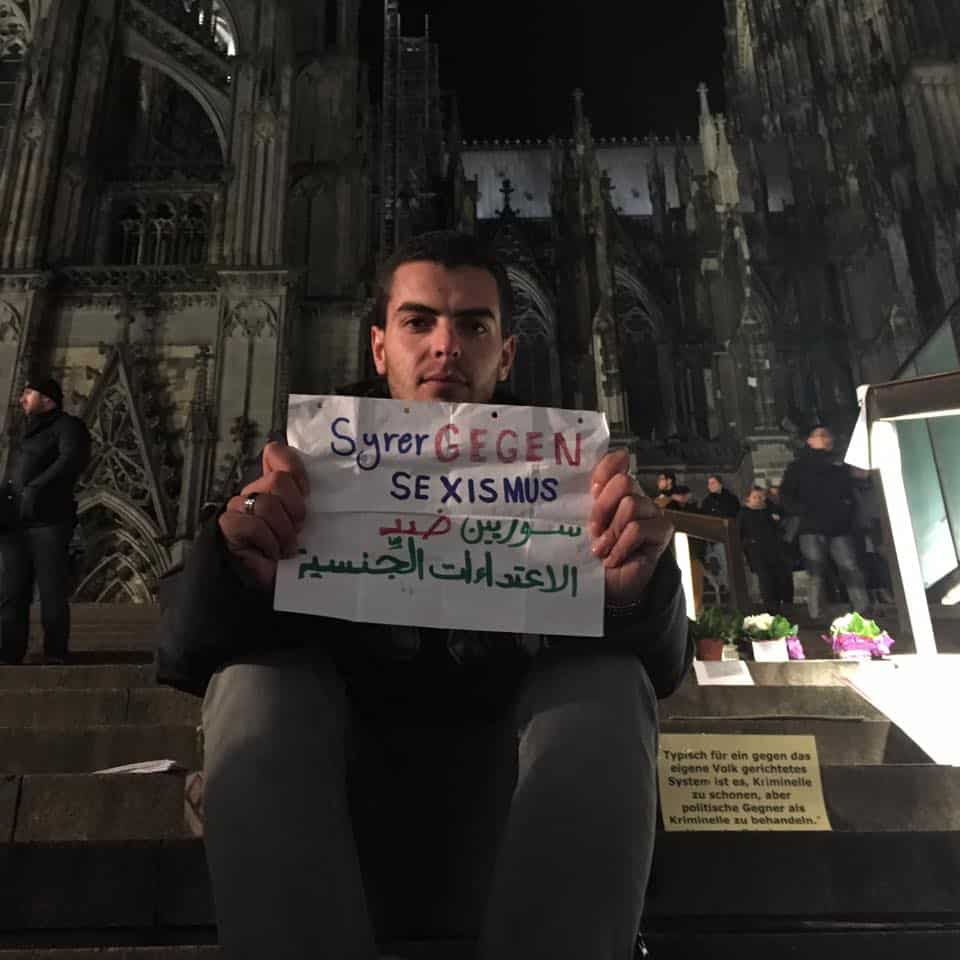 A Syrian man holds a sign showing respect for German culture and condemning attacks by his countrymen.